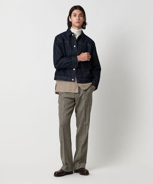 デニムジャケットの裾からシャツを見せる着こなしの男性