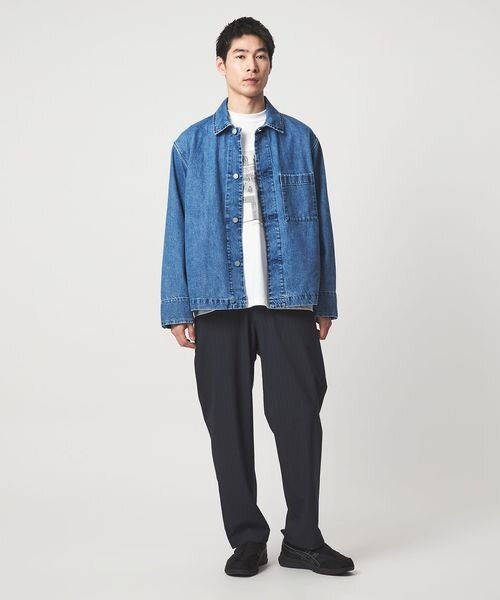 デニムジャケットにテーパードシルエットのパンツをあわせた男性