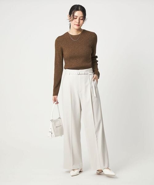 ブラウンのニットをタックインした女性