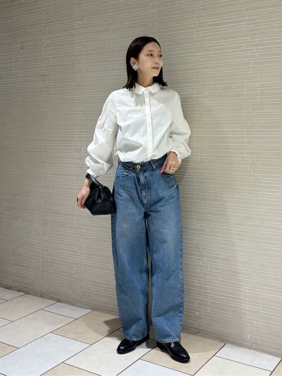 白ブラウスにデニムパンツをあわせた女性