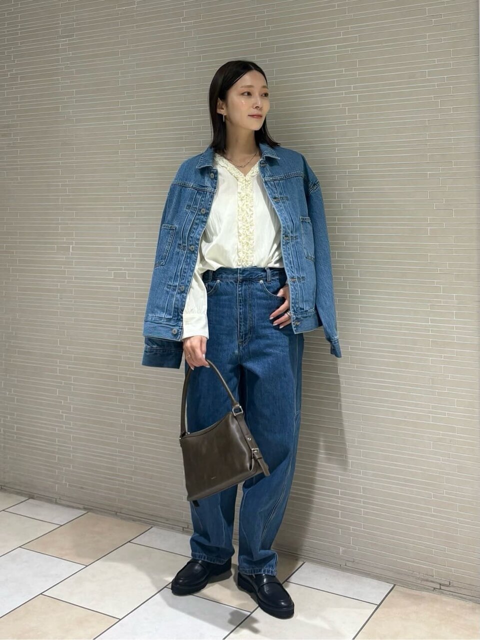 白ブラウスにデニムジャケットをあわせた女性