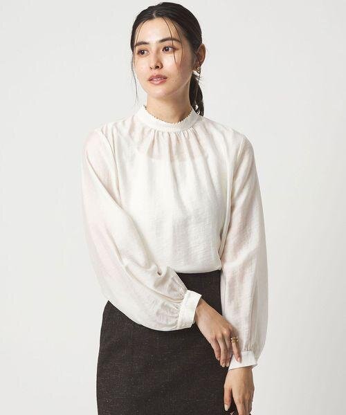 白ブラウスに白のインナーをあわせた女性