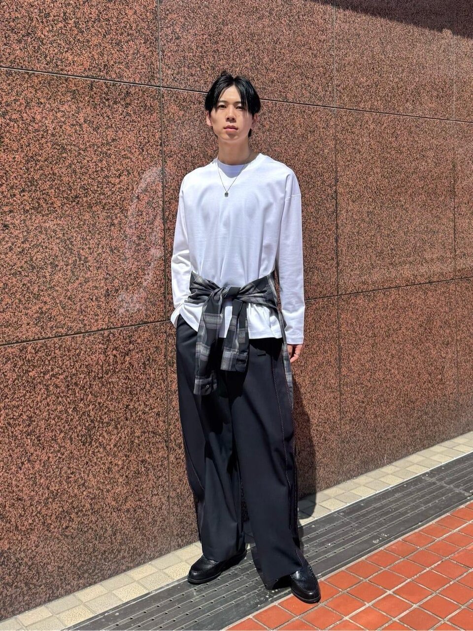 チェック柄のシャツを腰に巻く男性