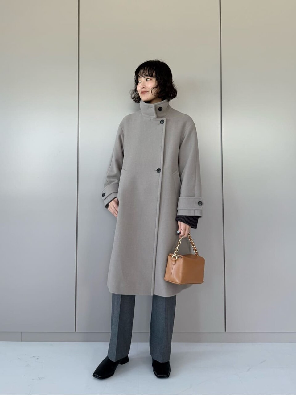 スタンドカラーコートとパンツを着た女性