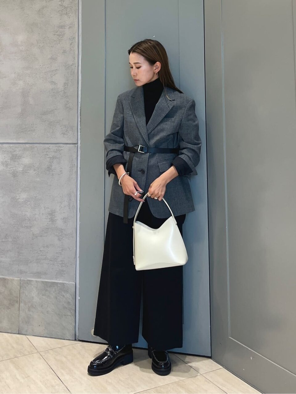 ベルト付きジャケットとパンツを着た女性