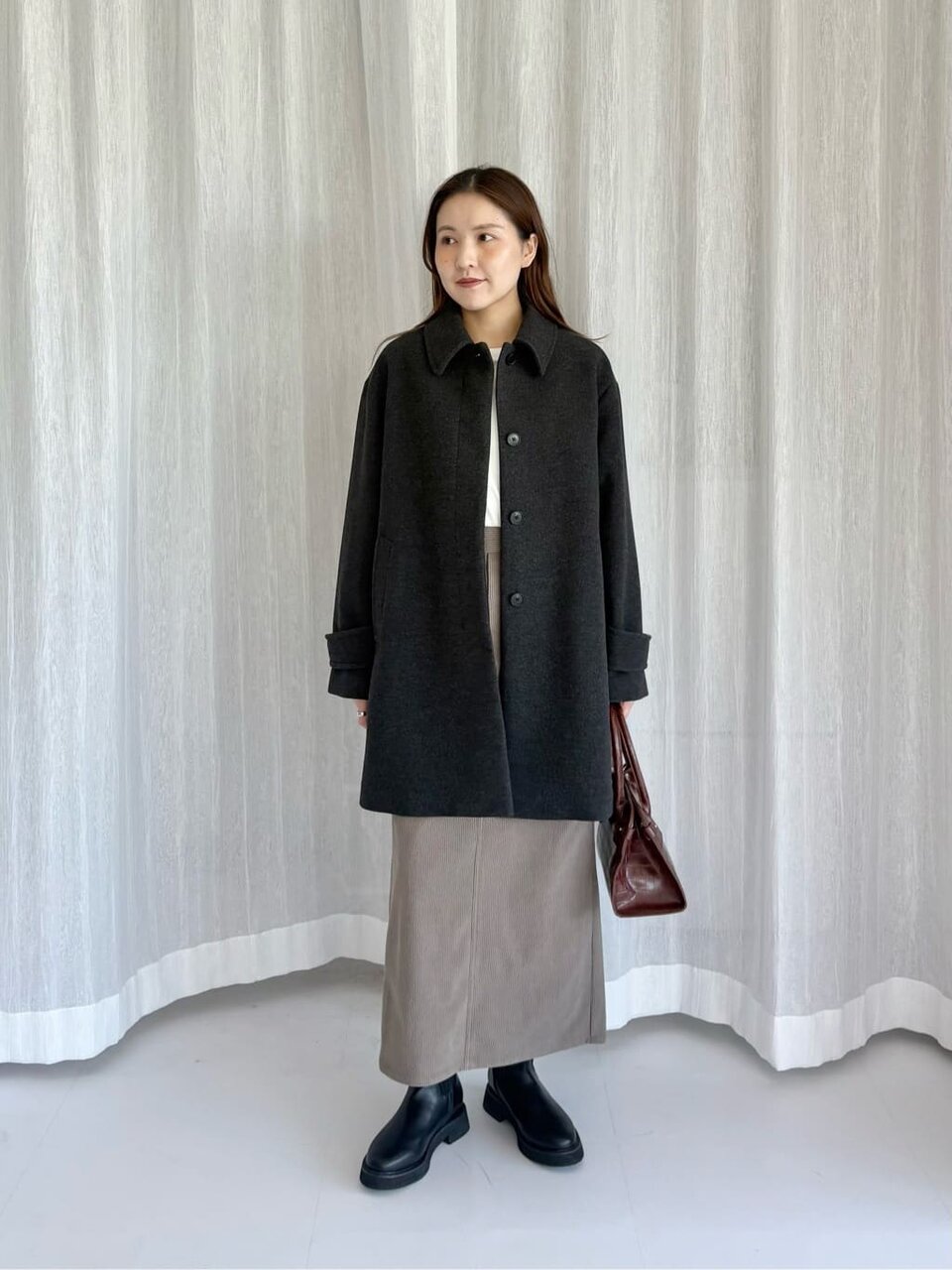 ステンカラーコートとタイトスカートを着た女性