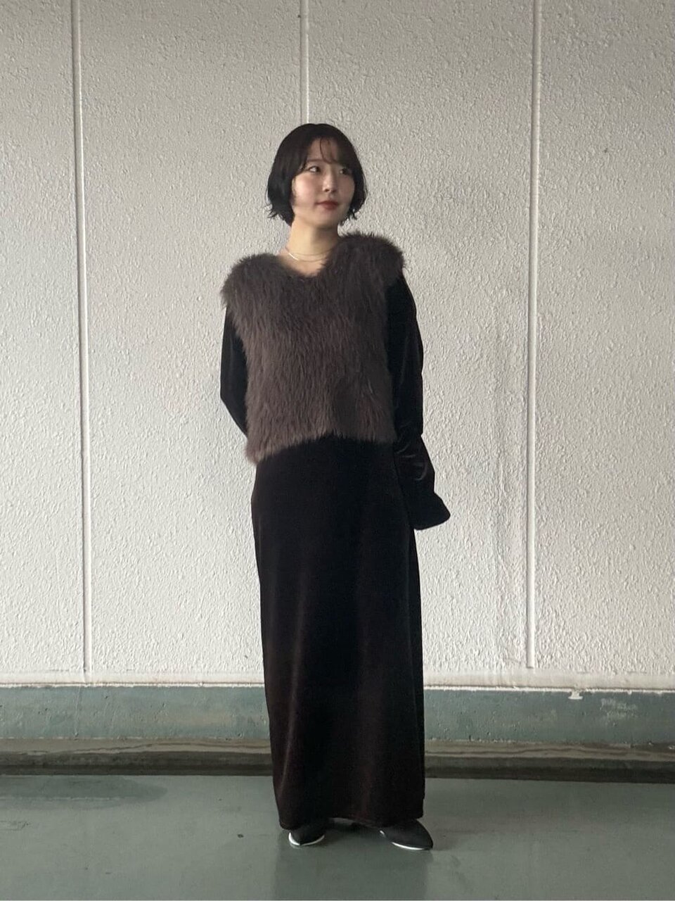 フェイクファーベストとベルベットワンピースを着た女性