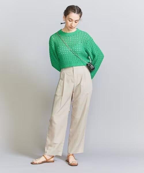 グリーンのニットとベージュパンツを着た女性