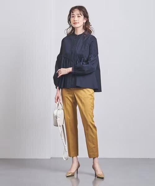 黒のブラウスとベージュパンツを着た女性