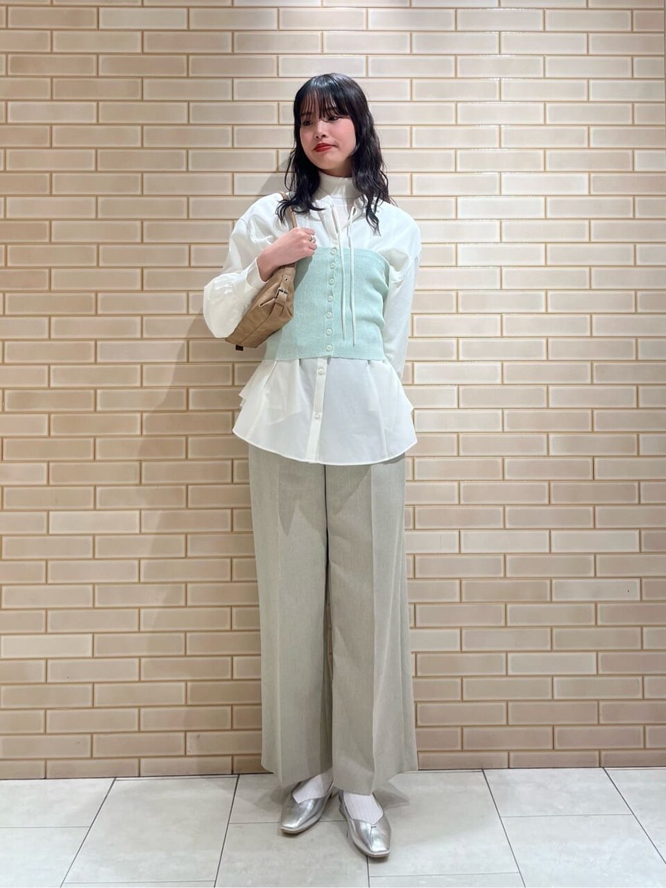 シアーシャツとニットビスチェを着た女性