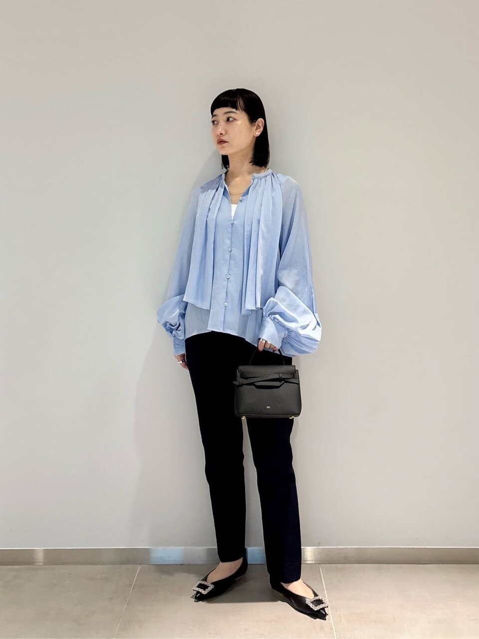 ブルーのシアーシャツとテーパンどパンツを着た女性