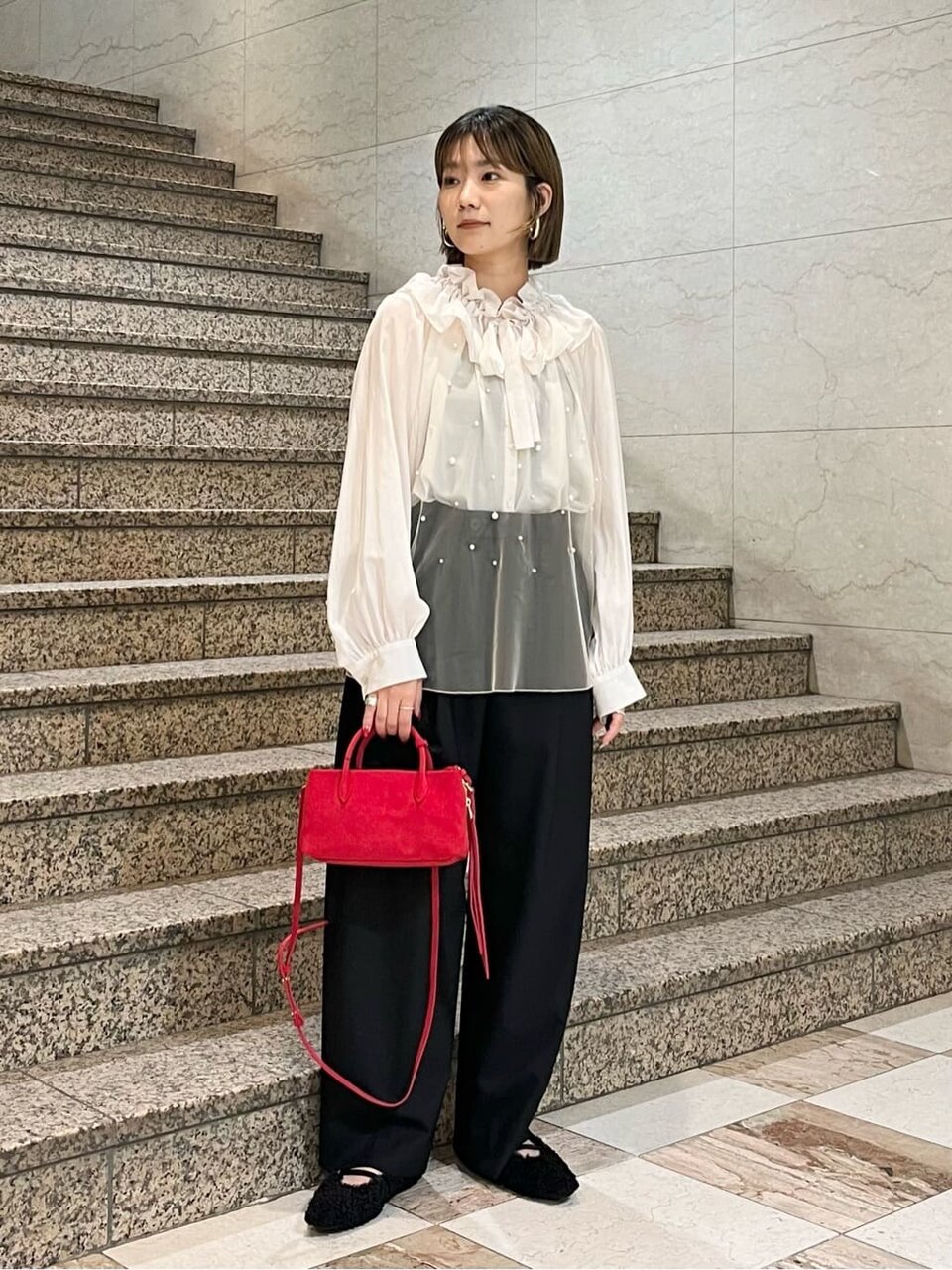 シアーブラウスとワイドパンツを着た女性