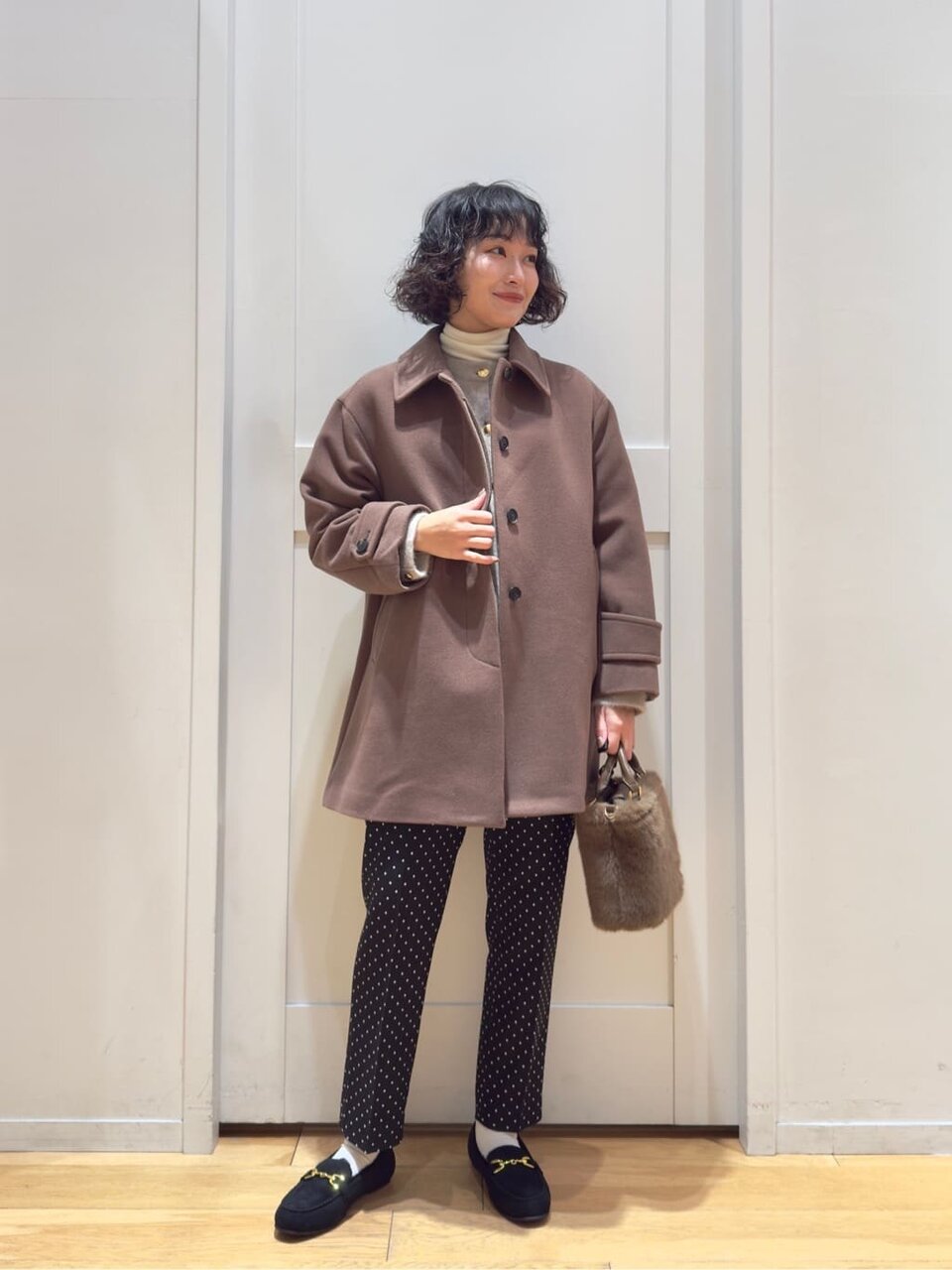 ステンカラーコートとテーパードパンツを着た女性