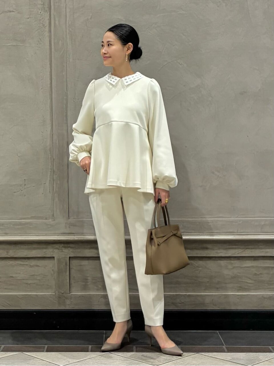 ペプラムブラウスととテーパードパンツを着た女性