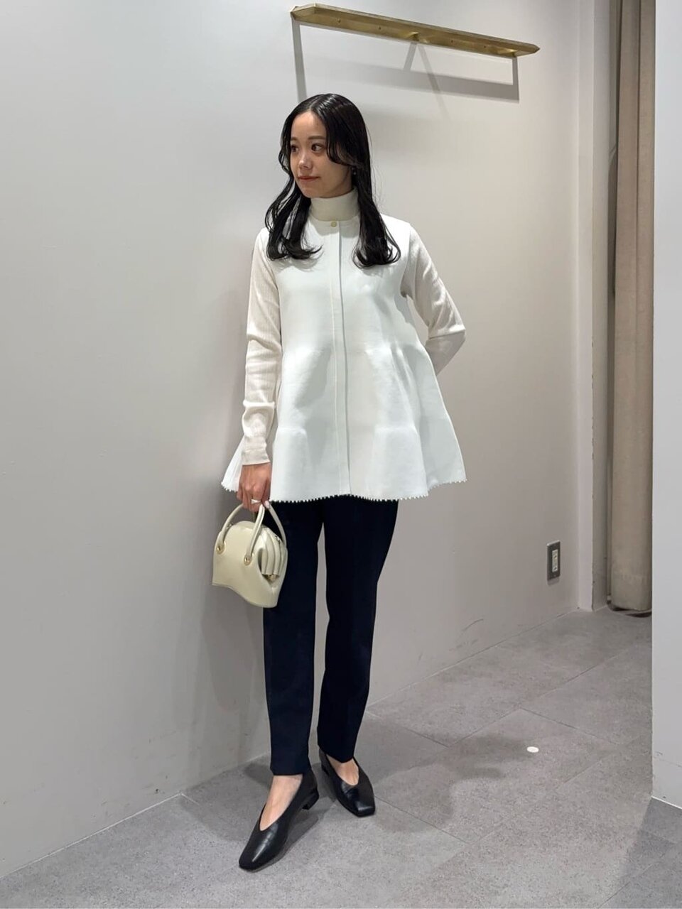 ペプラムニットとテーパードパンツを着た女性