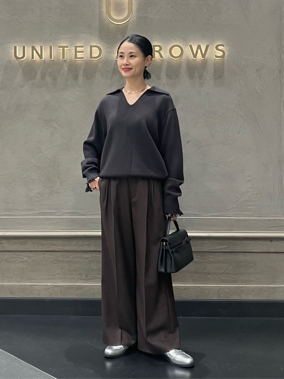 スキッパーニットとワイドパンツを着た女性