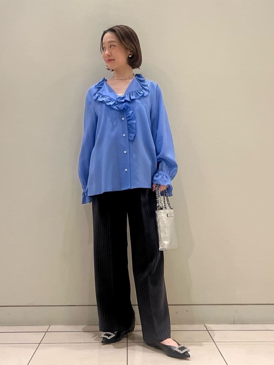 フリルブラウスとスラックスを着た女性