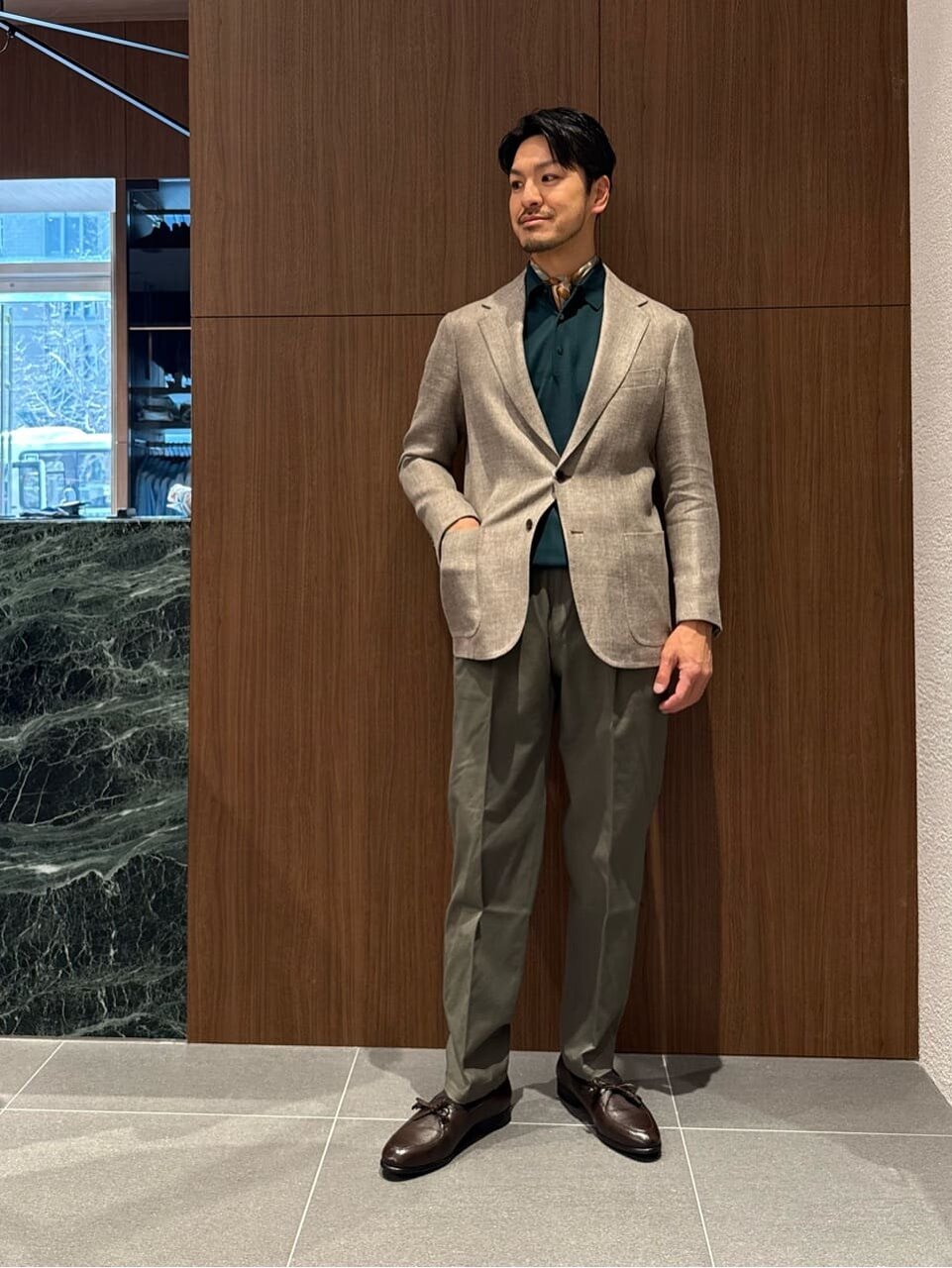 ベージュジャケットにオリーブカラーのパンツをあわせた男性