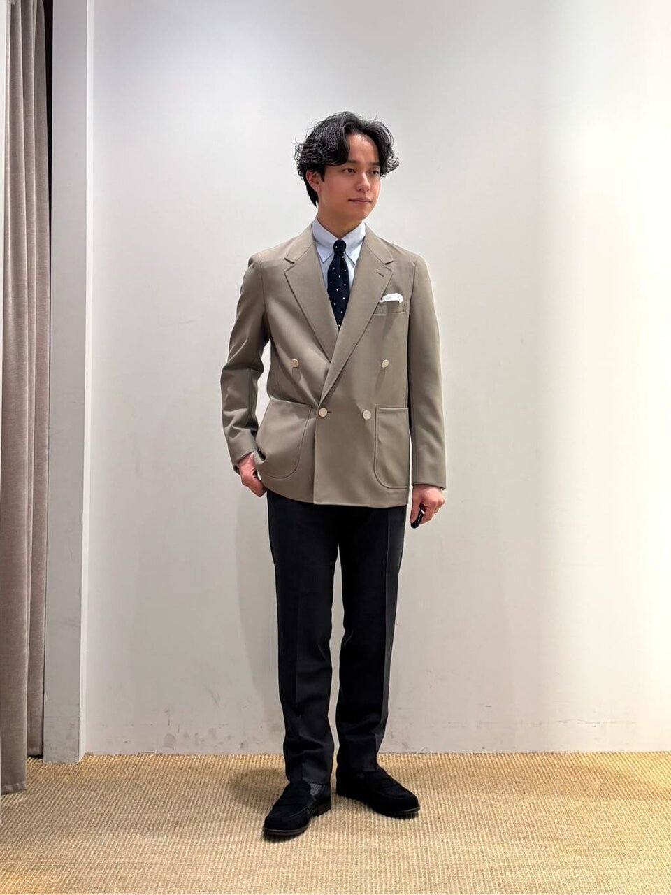 ベージュジャケットにネクタイをあわせた男性