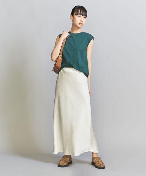 グリーンのノースリーブとマーメイドスカートを着用した女性