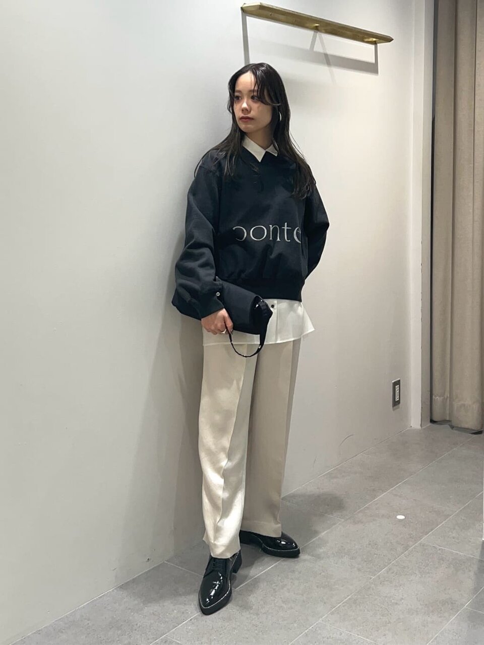 ロゴスウェットと白いパンツを着た女性