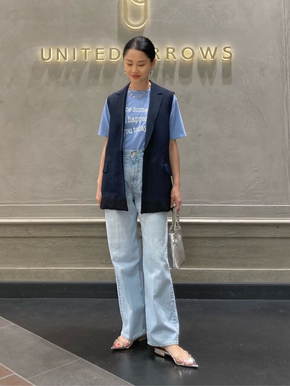 ロゴTシャツにテーラードベストをあわせた女性