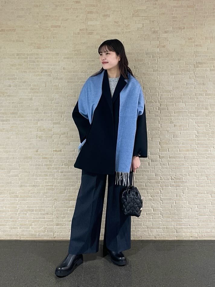 テーラードコートとブルーのマフラーをあわせた女性