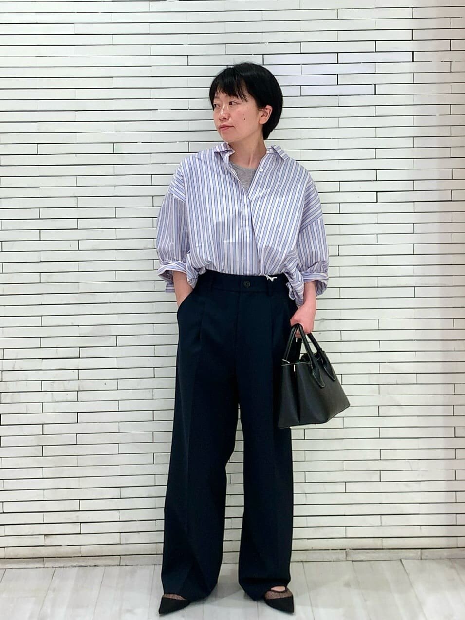 ストライプシャツとスラックスを着た女性