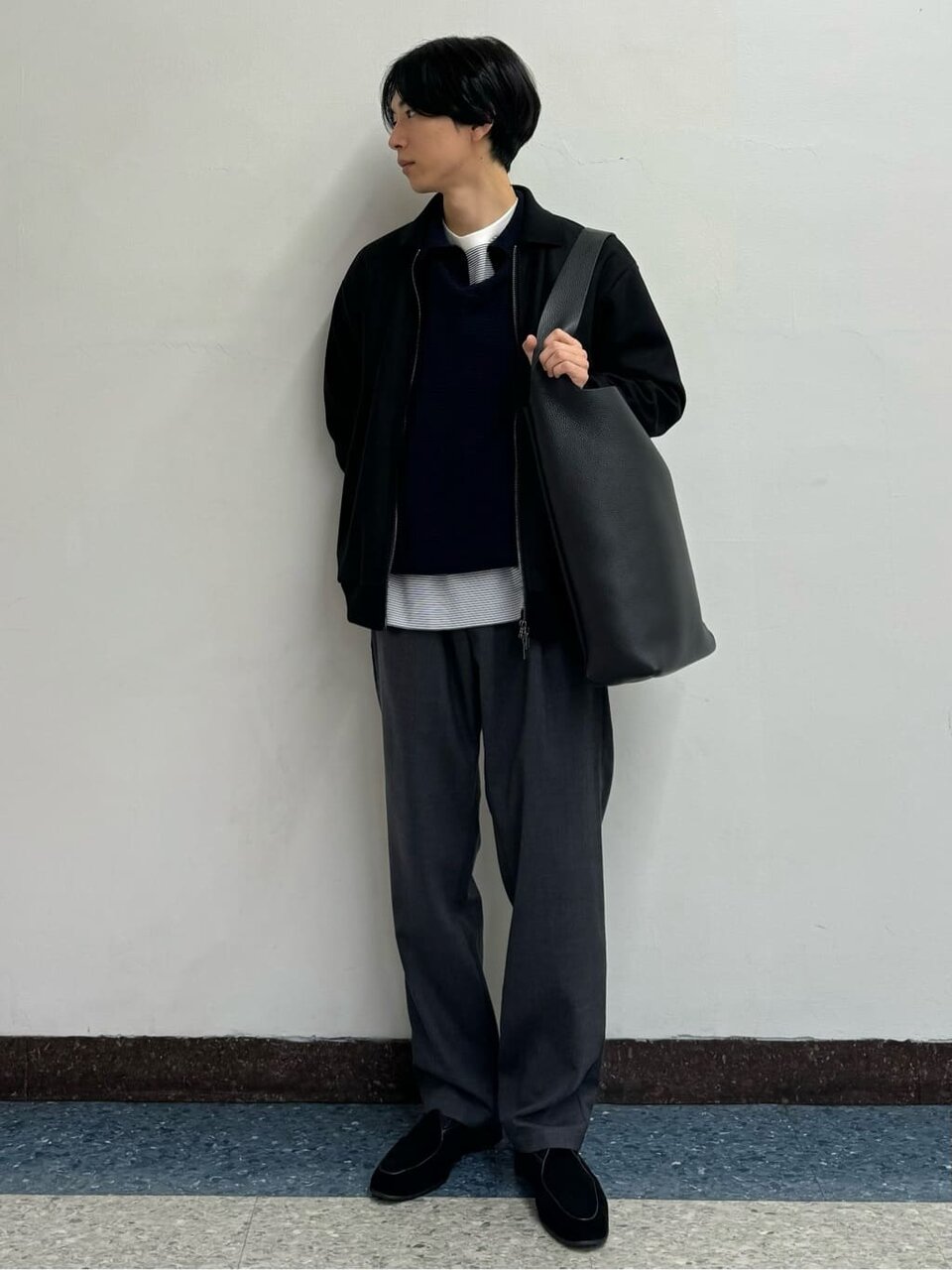 グレーパンツと黒いジップシャツを着た男性