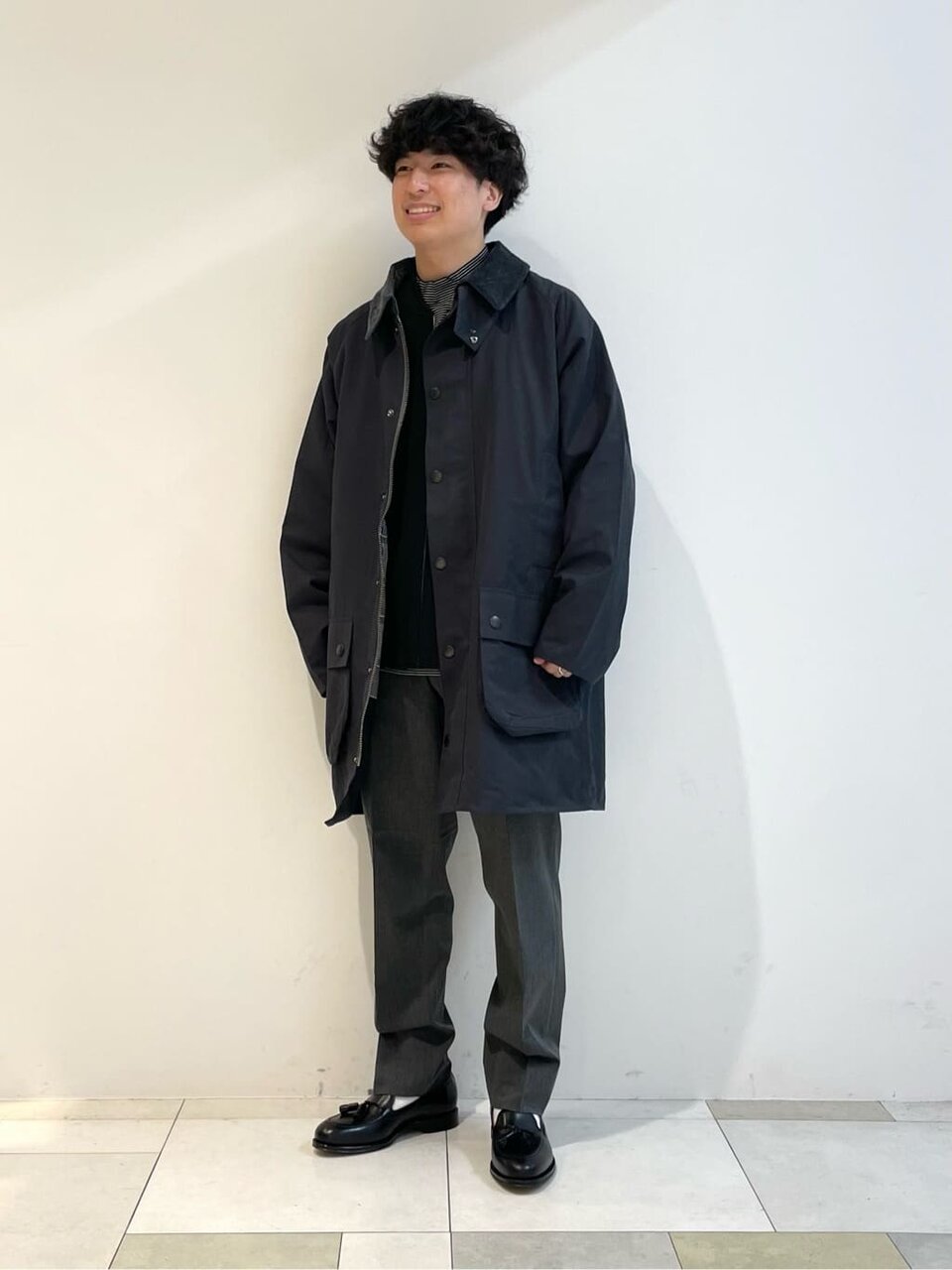 ダークグレーのゲームフェアコートとミディアムグレーのスラックスを着た男性