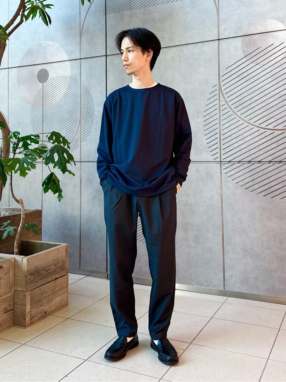 ネイビーのニットとグレーのユーティリティパンツを着た男性