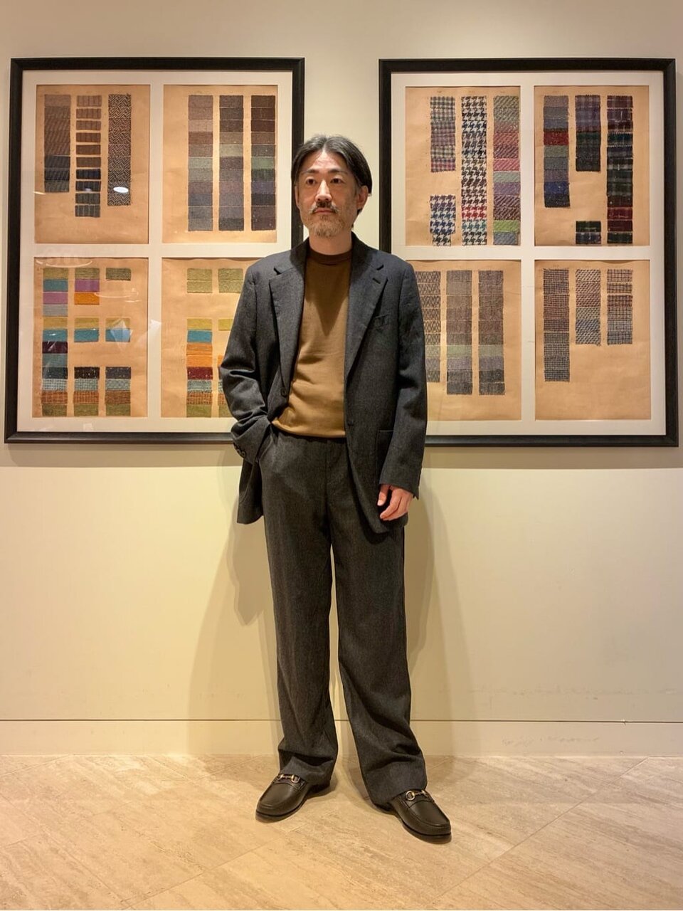 テーラードジャケットとグレーのパンツを着た男性