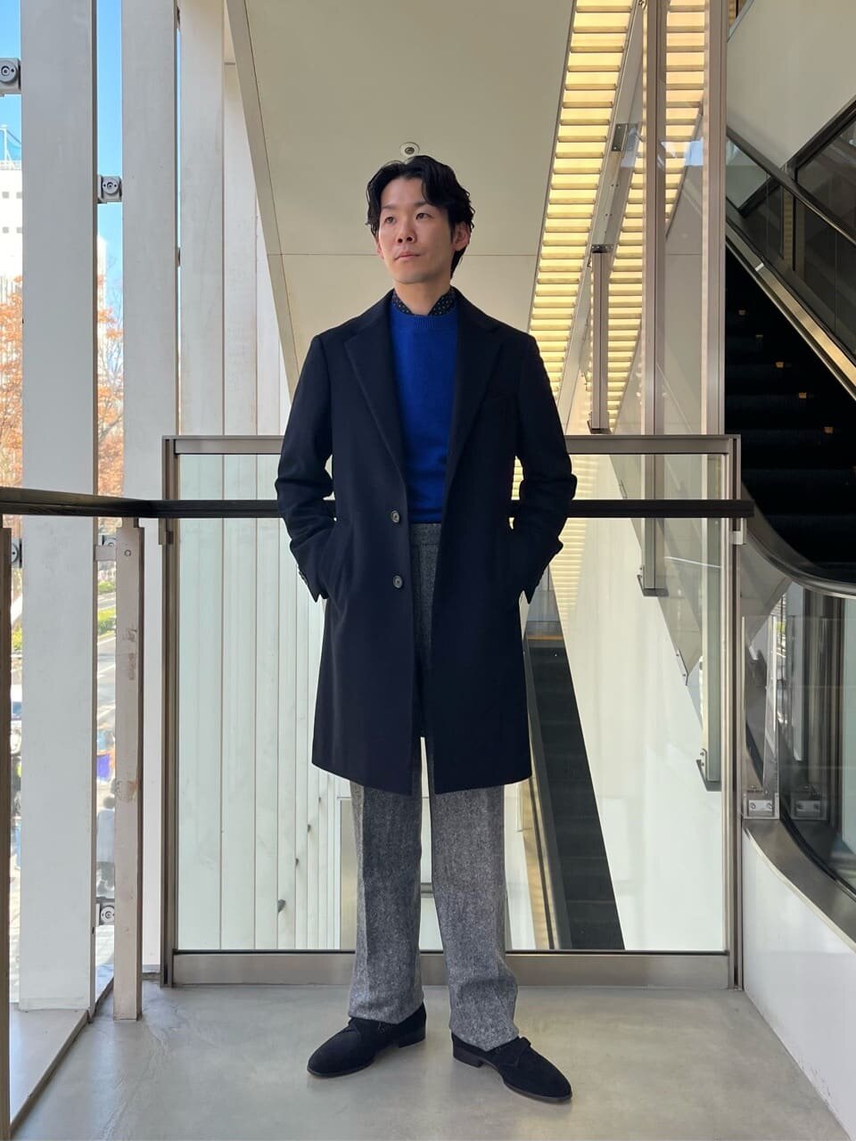 チェスターコートとグレーのパンツを着た男性