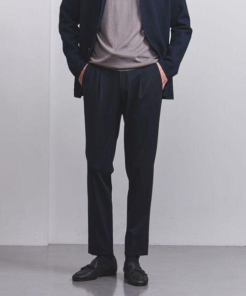 上品な光沢感のテーパードパンツを着用する男性