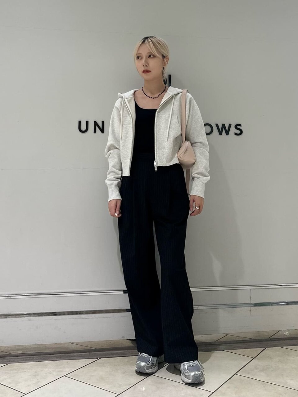 ライトグレーのパーカーとタックパンツを着た女性