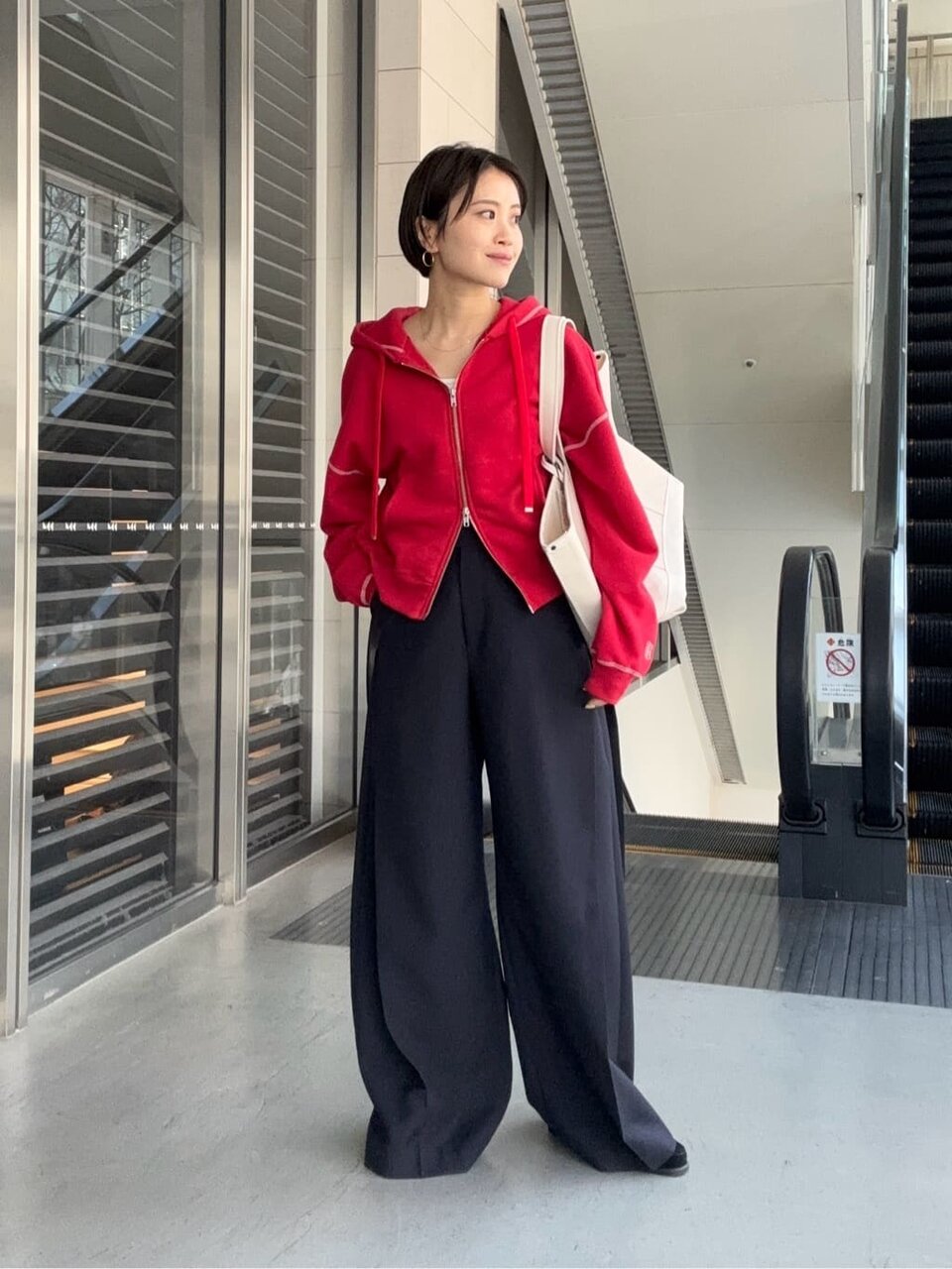 赤のパーカーと黒のワイドパンツを着た女性