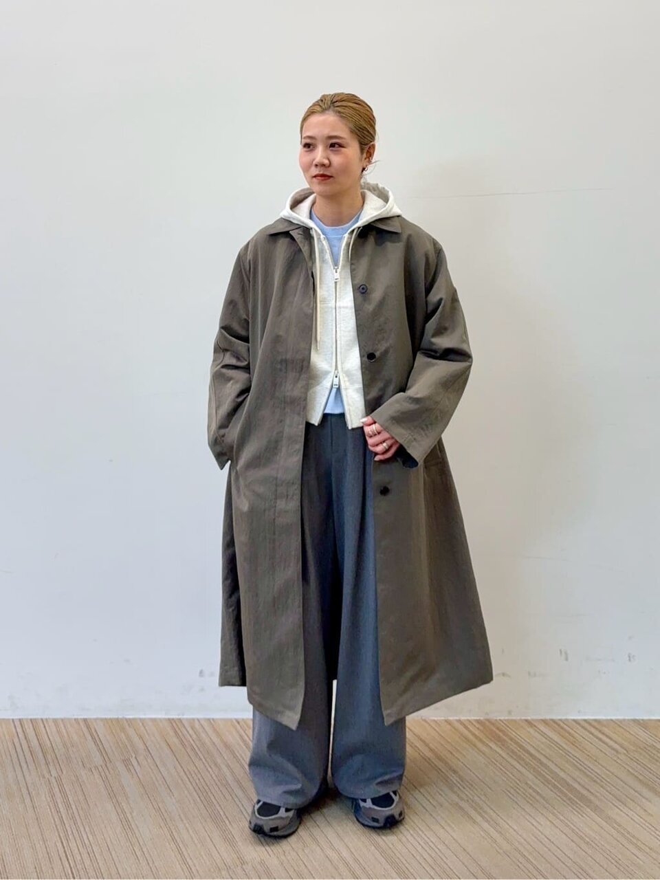 ステンカラーコートとパーカーを着た女性