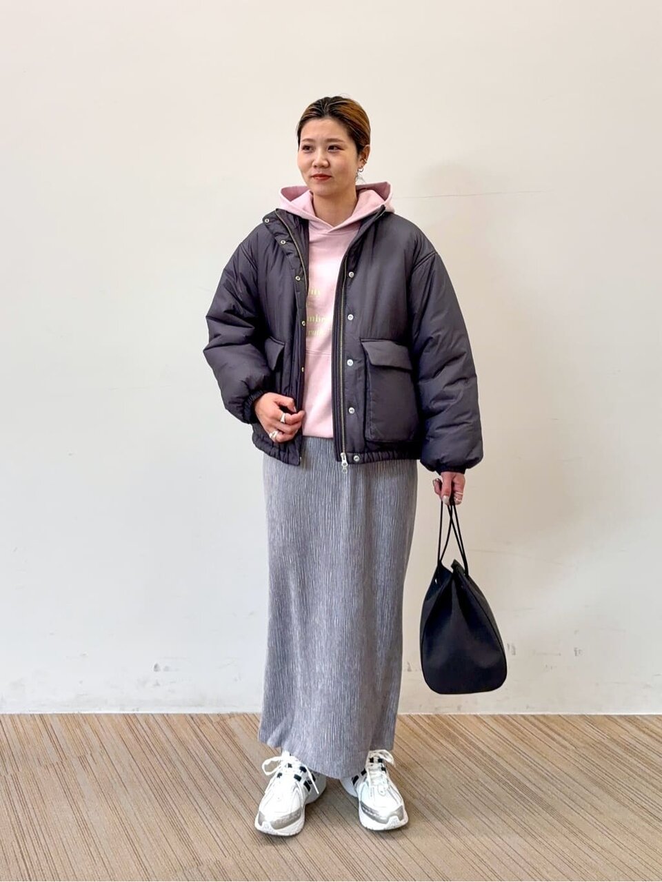 ピンクのパーカーとロングスカートを着た女性