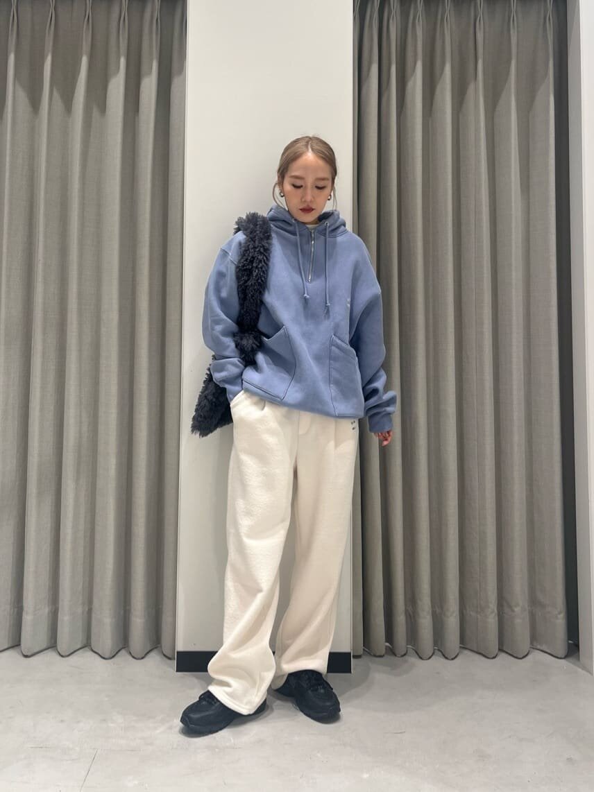 ブルーのパーカーと白いパンツを着た女性