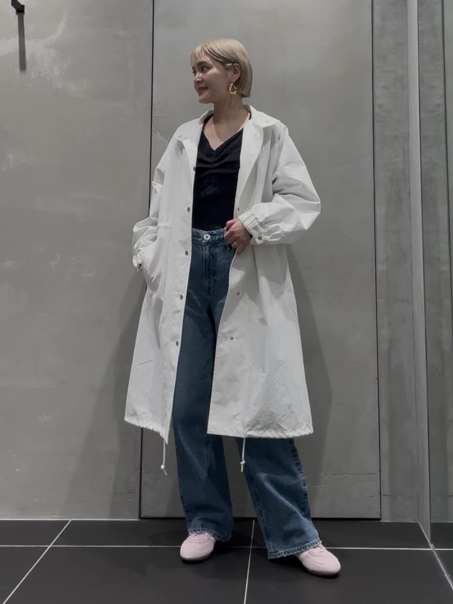 白のロングコートとワイドデニムを着た女性