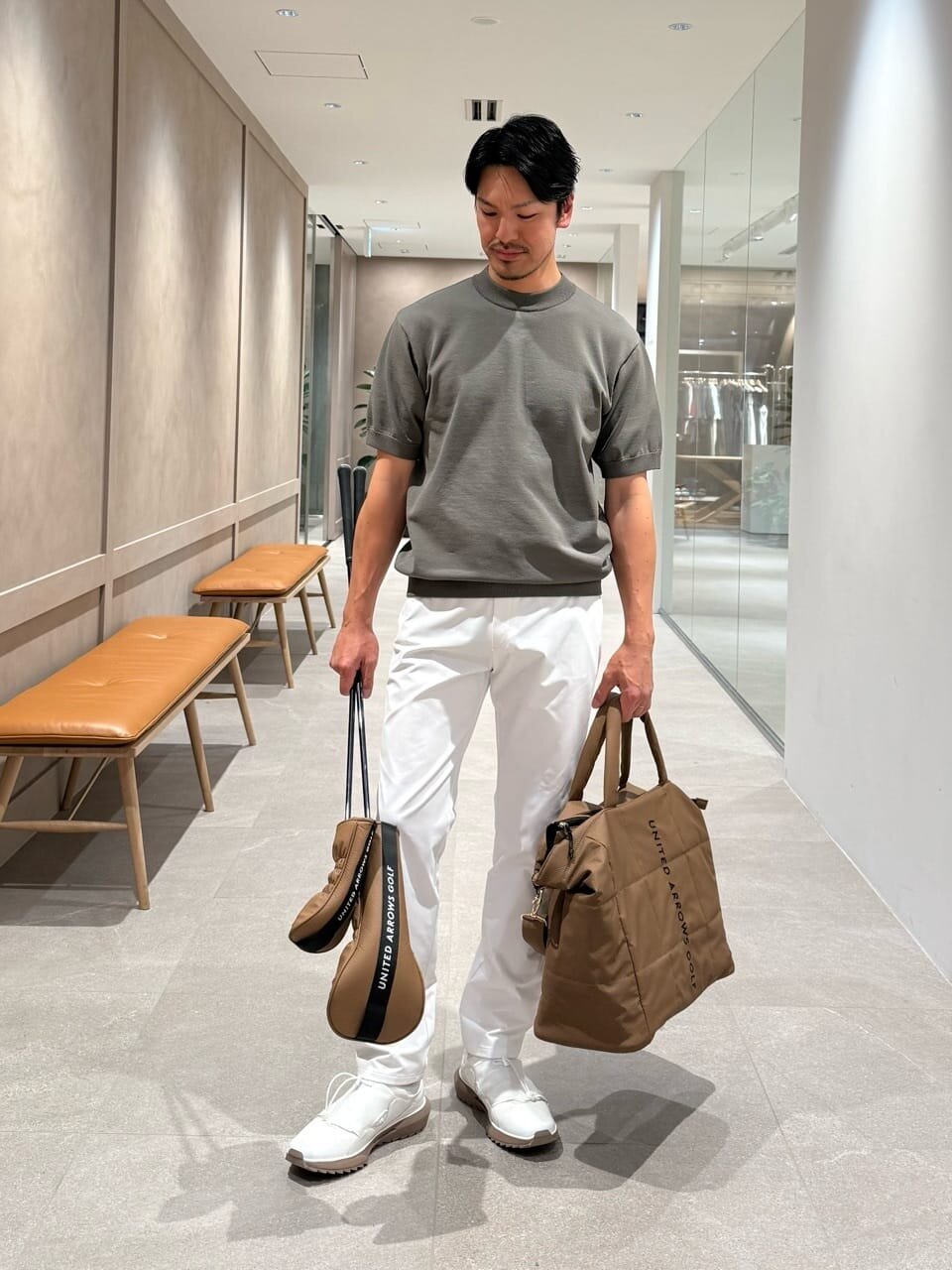 モックネック ニットと白いパンツを着た男性