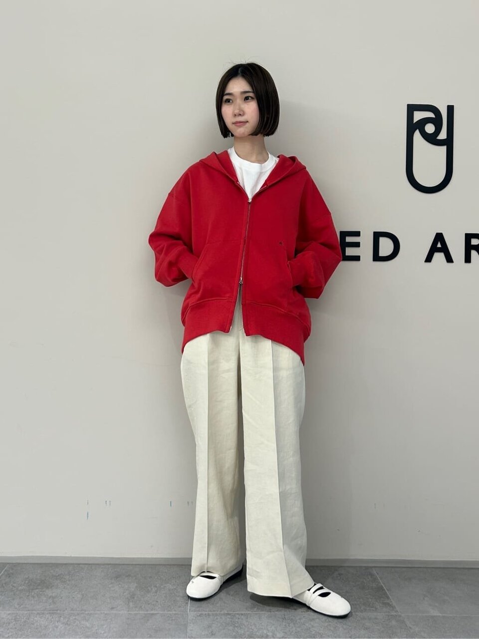 赤のパーカーと白いパンツを着た女性