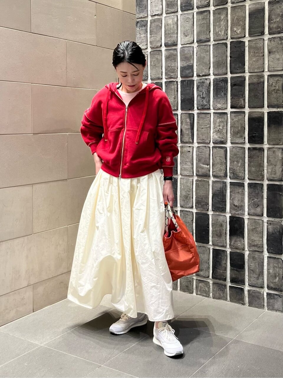 赤いパーカーと白いスカートの女性