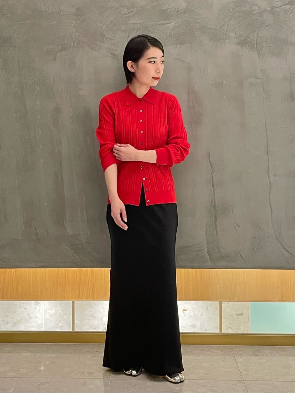 赤いカーディガンと黒のスカートを着た女性