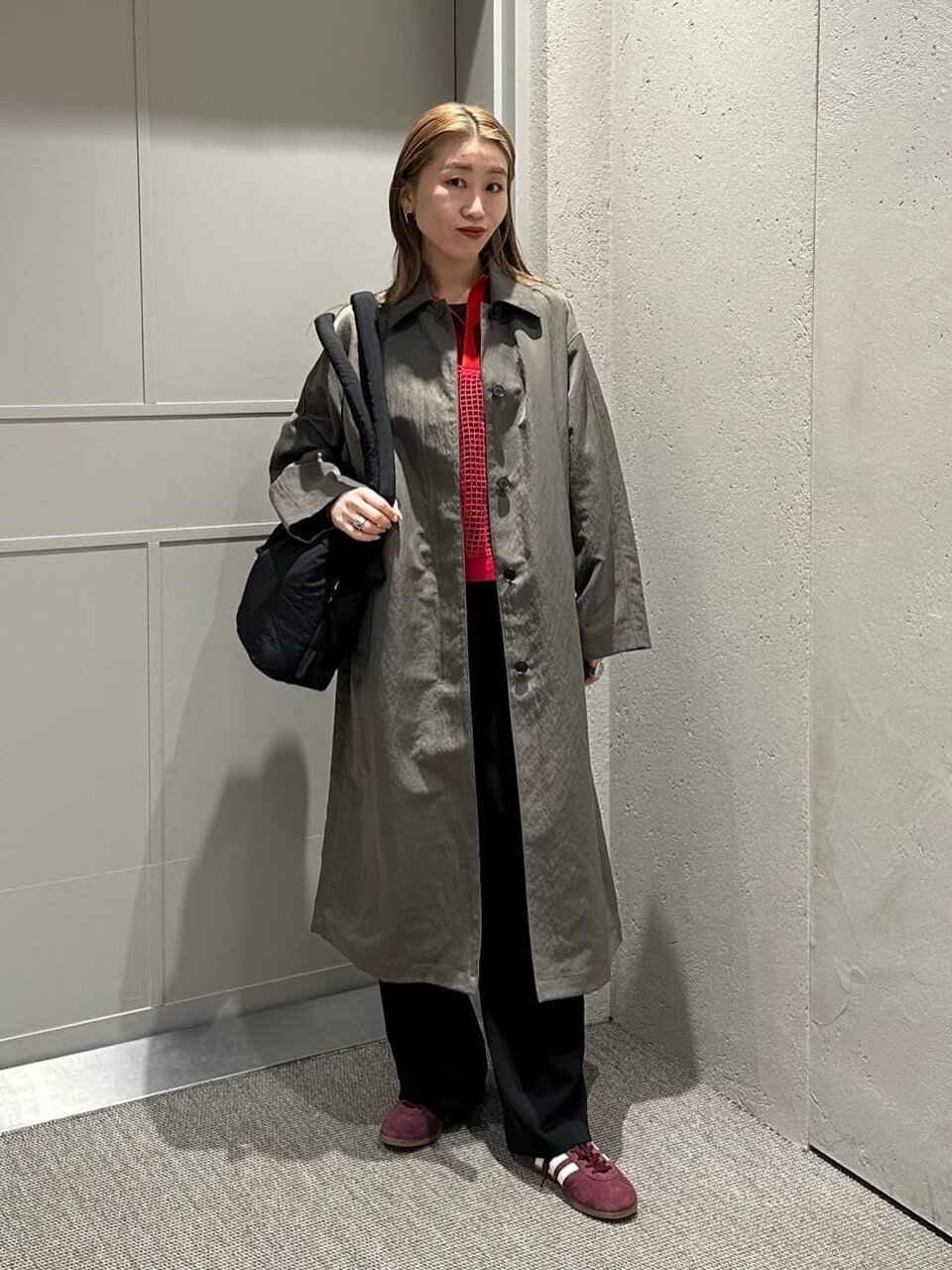 グレーのコートと赤いトップスを着た女性