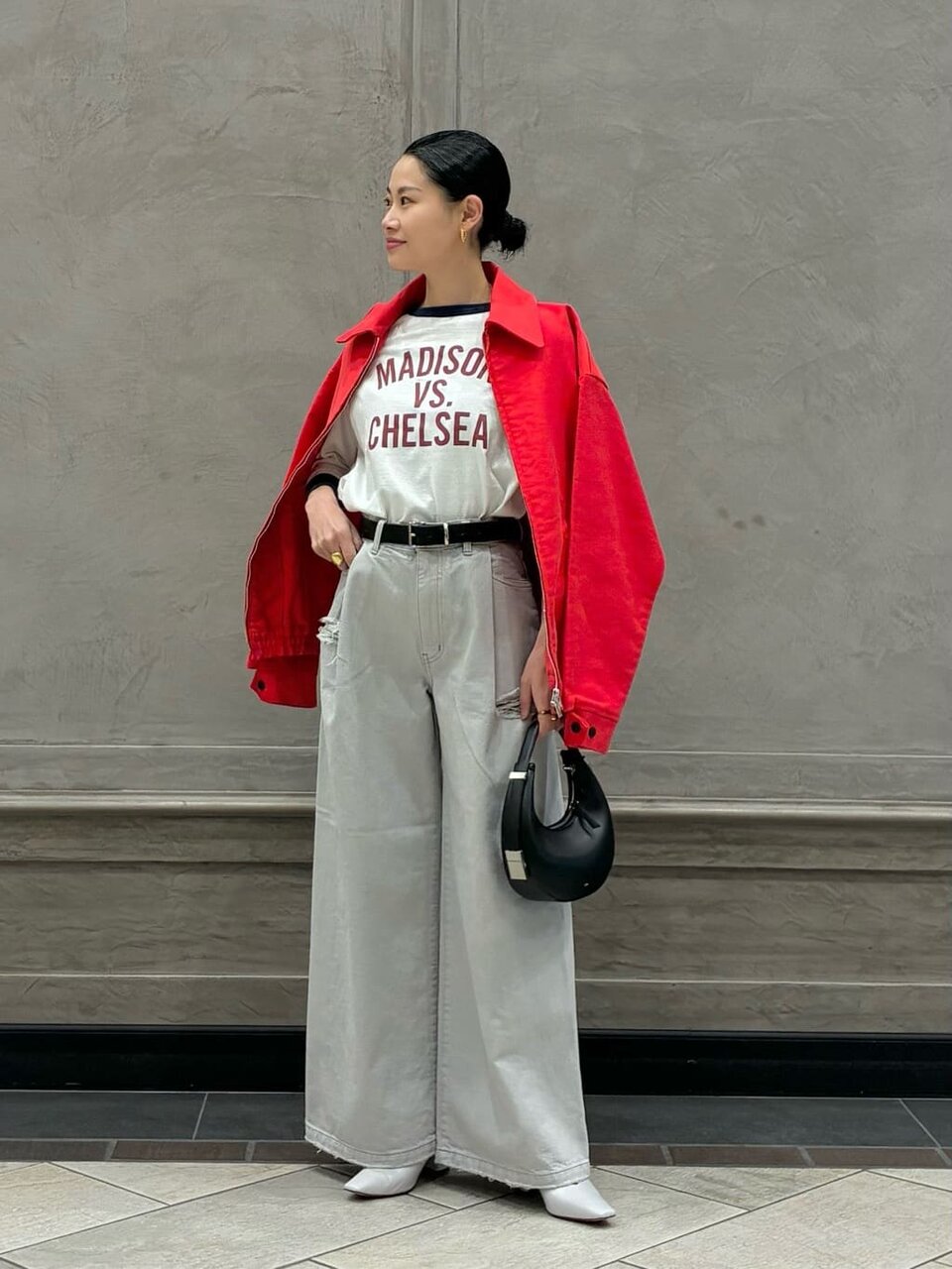 赤のブルゾンとグレーのパンツを着た女性