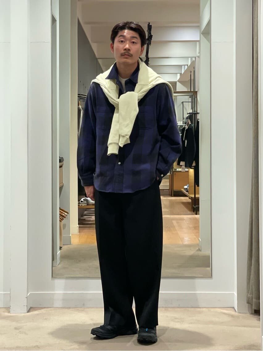 チェックシャツと肩掛けニットを着た男性