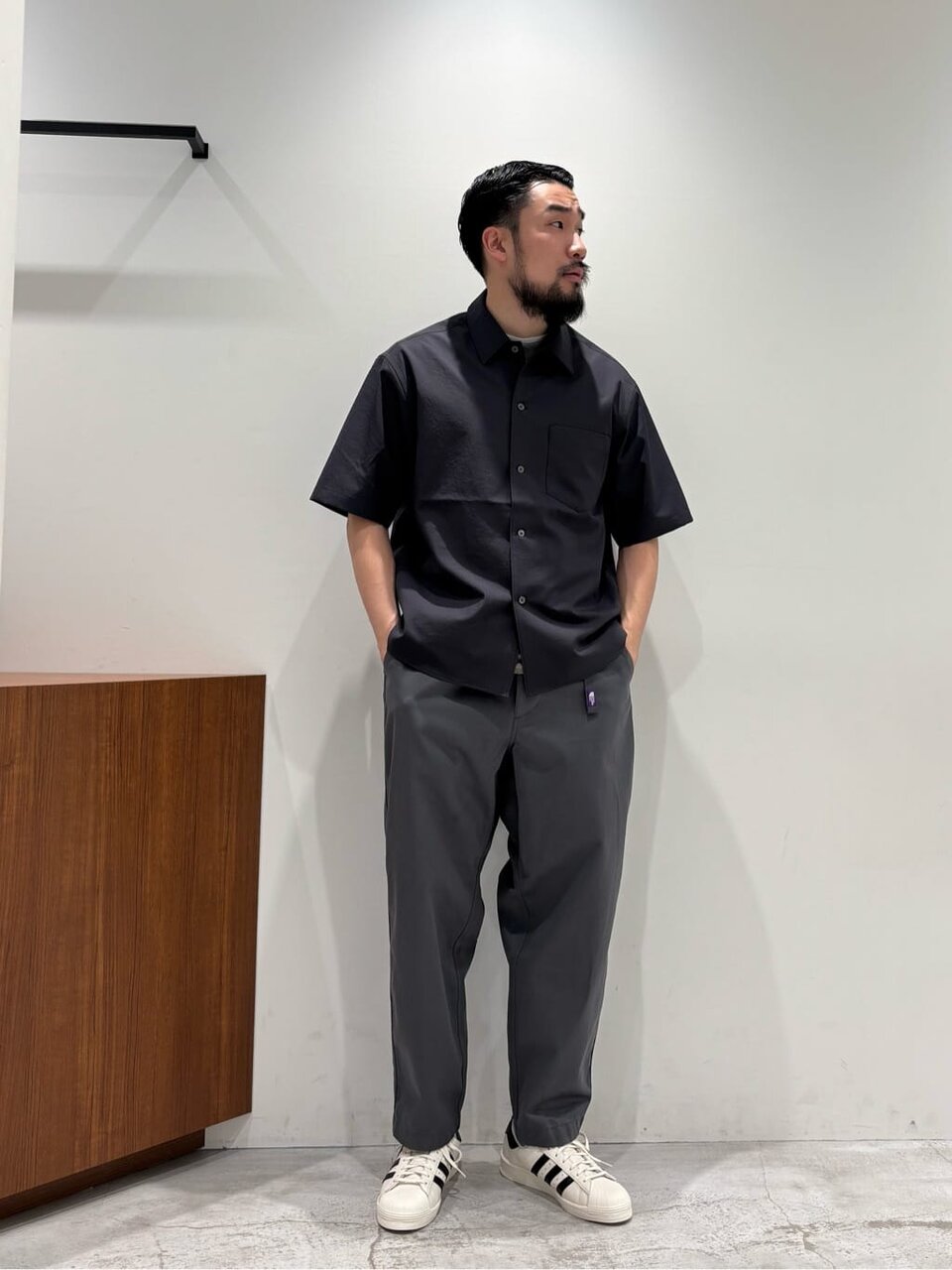 ダークグレーの半袖シャツとパンツを着た男性