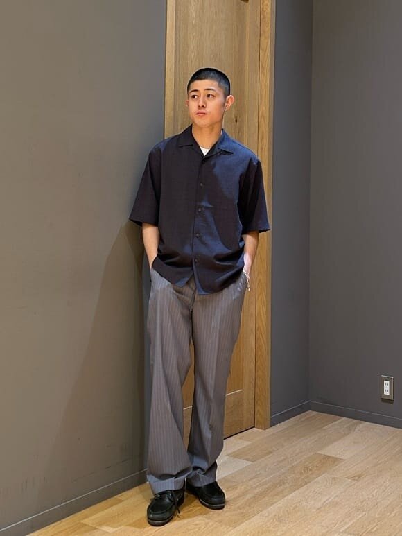 オープンカラーシャツとストライプパンツを着た男性