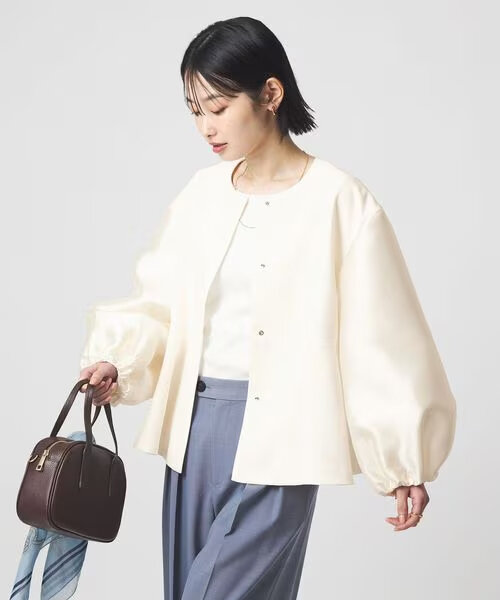 襟元の詰まったノーカラージャケットを着た女性